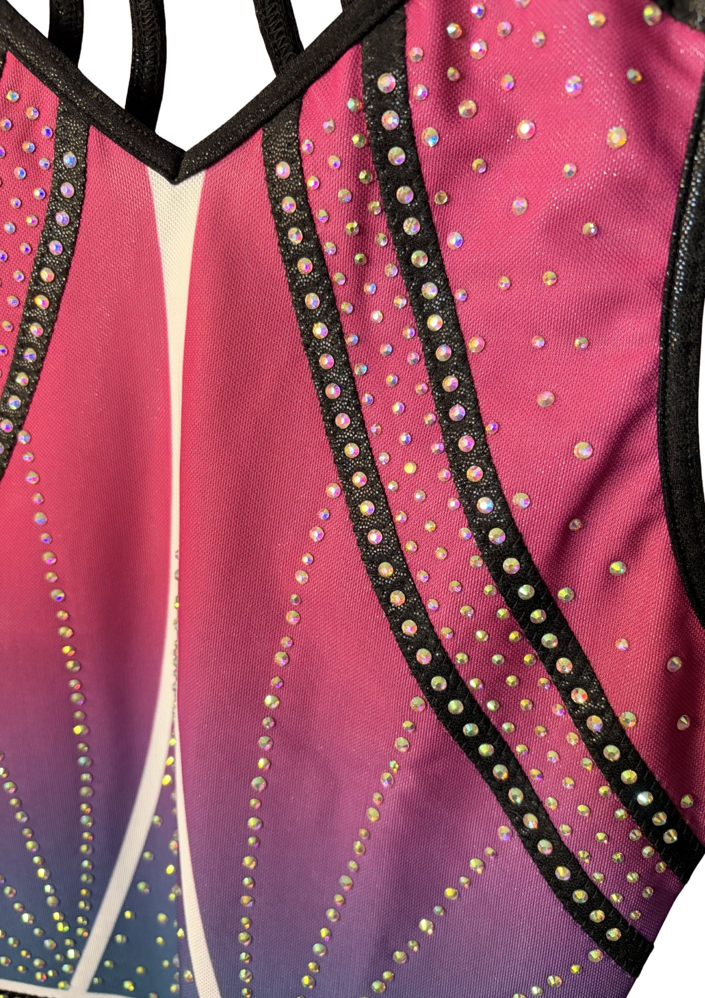 Close-up of a pink gymnastics leotard with black straps and colorful rhinestone details on a white background